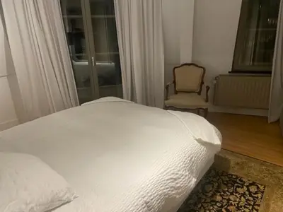a bedroom with a white bed and a chair at Duplex dernier étage avec terasse à deux pas de la grand place in Brussels