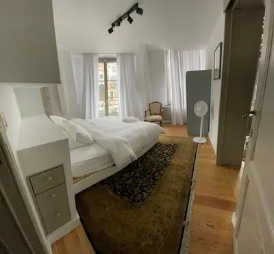 a white bedroom with a bed and a rug at Duplex dernier étage avec terasse à deux pas de la grand place in Brussels