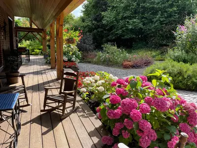 a porch with a bunch of flowers and chairs at Hallerbos B&B in Bluebell Forest in Halle