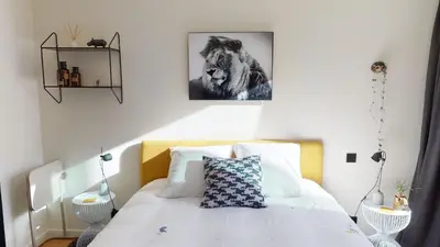 a bedroom with a white bed with a lion picture on the wall at Suite lumineuse à Saint-Gilles in Brussels