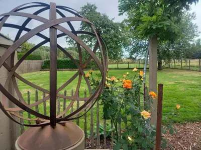 a metal sphere next to a fence with flowers at Natuurschoon Vakantiewoning Moorsel in Moorsel