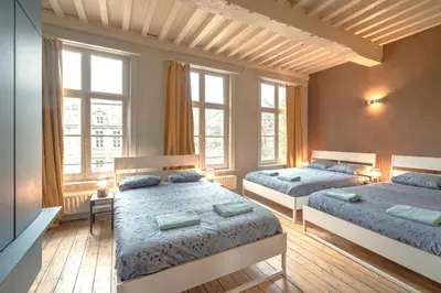 a bedroom with two beds and two windows at The Charming Hendrik Square Apartments in Antwerp