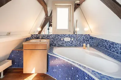 a blue tiled bathroom with a tub and a window at The Charming Hendrik Square Apartments in Antwerp