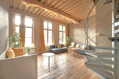 a living room with a staircase and a couch and chairs at The Charming Hendrik Square Apartments in Antwerp
