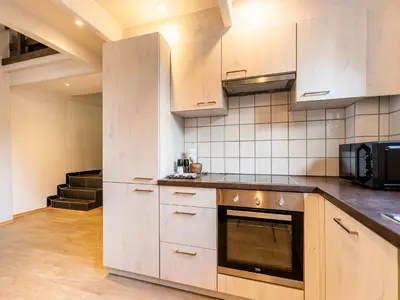 a kitchen with white cabinets and a stove top oven at Herselt Garden Shed Retreat in Herselt