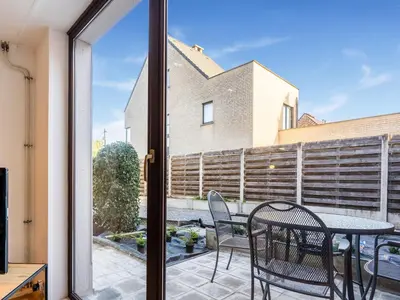 a glass door leading to a patio with a table and chairs at Herselt Garden Shed Retreat in Herselt