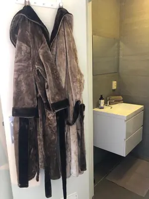 a robe hanging on a wall next to a sink at Logies Dampoort in Ghent