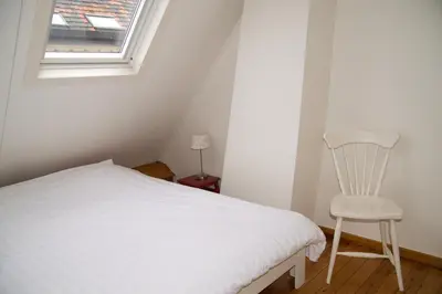 a bedroom with a white bed and a chair at Plezantwerpen, Zuiderzin in Antwerp