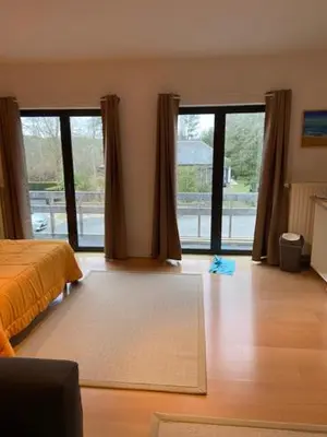 a bedroom with a bed and sliding glass doors at narcisses in Sint-Genesius-Rode