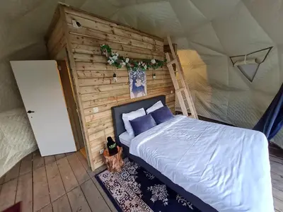 a bedroom with a bed and a ladder in a tent at Parkhoeve Glamping in Ham