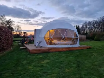 a tent in a field with people sitting in the grass at Parkhoeve Glamping in Ham
