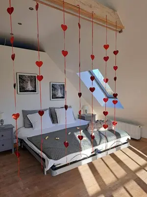 a bedroom with a bed with red hearts hanging from the ceiling at Domein Den Buiten Bed And Breakfast DnD in Sint-Niklaas
