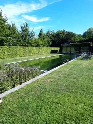 a garden with a pond and a fence and grass at Domein Den Buiten Bed And Breakfast DnD in Sint-Niklaas