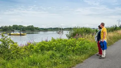 two people standing on a path looking at a river at B&B De Schorre in Boom