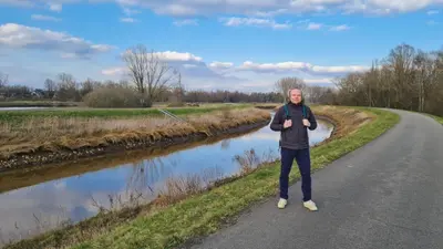 a man standing on a road next to a river at B&B De Schorre in Boom