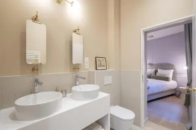 a white bathroom with two sinks and a bed at SHWAY - Le Marnix in Antwerp