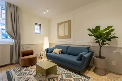a living room with a blue couch and a potted tree at SHWAY Le Pierre in Antwerp