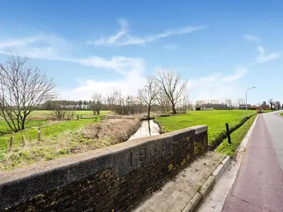 a stone wall next to a road and a field at Merksplas Villa with Terrace in Merksplas