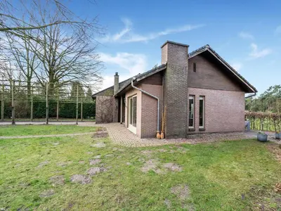 a brick house with a grass yard in front of it at Merksplas Villa with Terrace in Merksplas
