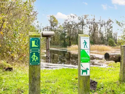 two signs on posts in front of a body of water at Alverwege in Merksplas