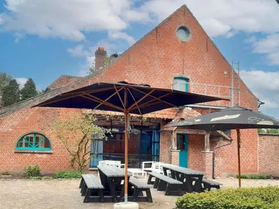a picnic table with an umbrella in front of a building at Alverwege in Merksplas