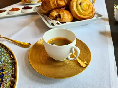 a cup of coffee on a plate on a table with pastries at The Old Beech in Antwerp
