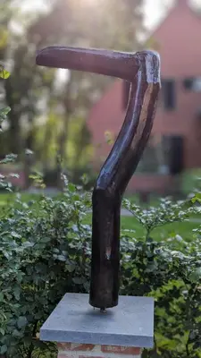 a statue of a long stick sitting on top of a stone block at Van Horick in Baal