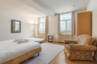 a bedroom with a bed and a chair and windows at TOP& ruim duplex woning in PATERSHOL,centrum Gent! in Ghent