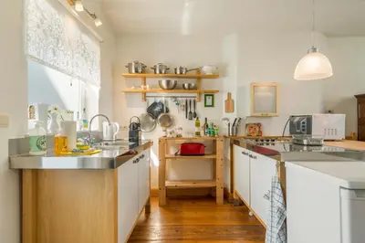 a kitchen with white counters and wooden floors at TOP& ruim duplex woning in PATERSHOL,centrum Gent! in Ghent
