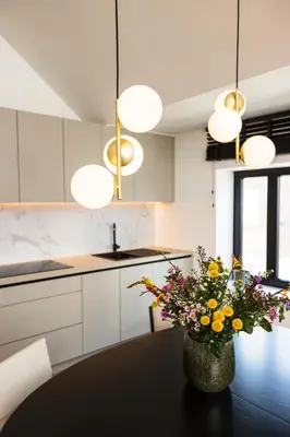 a kitchen with white cabinets and a black table with flowers at The lodge Morris in Leuven