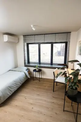 a bedroom with a bed and a table and two windows at The lodge Morris in Leuven