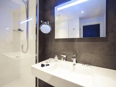 a bathroom with a sink and a shower and a mirror at Mercure Hotel Brussels Centre Midi in Brussels