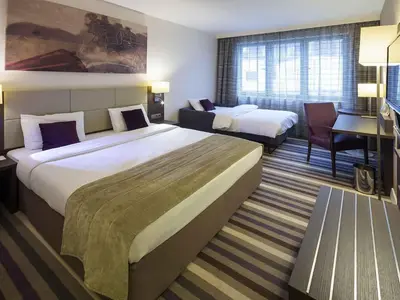 a hotel room with two beds and a desk at Mercure Hotel Brussels Centre Midi in Brussels