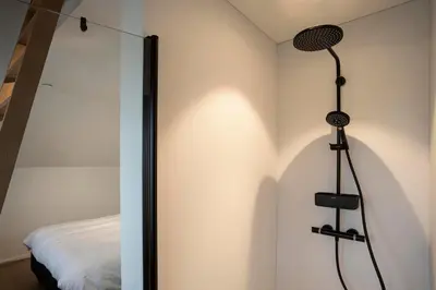 a shower in a bedroom next to a bed at stek&stoof in Sint-Pauwels