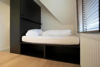 a bed with white sheets and pillows sits in a room at stek&stoof in Sint-Pauwels