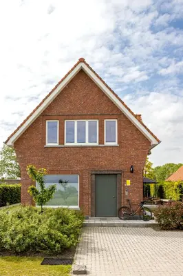 a brick house with a garage at stek&stoof in Sint-Pauwels
