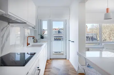a white kitchen with white counters and a window at Molière Design Residence in Brussels