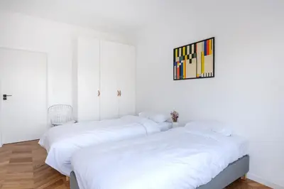 two beds in a room with white walls at Molière Design Residence in Brussels