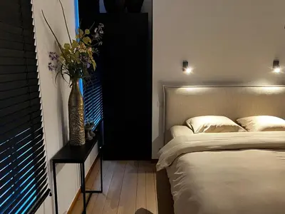 a bedroom with a bed and a vase of flowers on a table at Maison Gand in Ghent