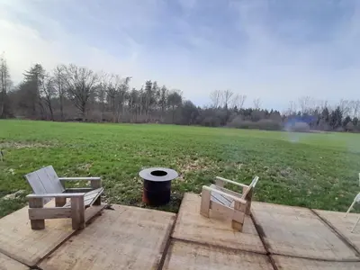 two chairs and a trash can on a wooden deck with a field at Kromven On Wheels in Merksplas