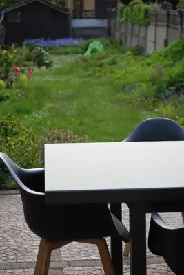 a white table and a black chair in a garden at Gastenkamers huYze K in Zottegem