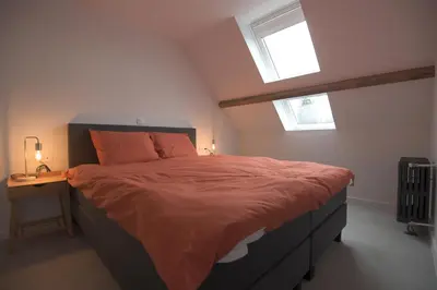 a bedroom with a bed with orange sheets and a table at Gastenkamers huYze K in Zottegem