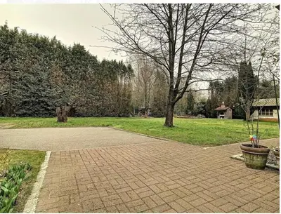 a brick walkway in a park with a tree at Panoramic Bungalow Sint Gillis-Waas in Sint-Gillis-Waas