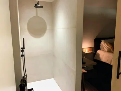 a bathroom with a shower and a bed in a room at B&B 't klein GELUK in Ham