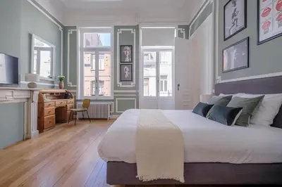 a bedroom with a large white bed and a desk at La Calamande En Ville in Brussels