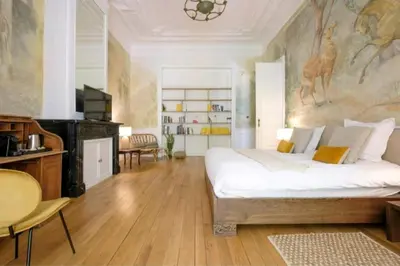 a bedroom with a large bed with a painting on the wall at La Calamande En Ville in Brussels