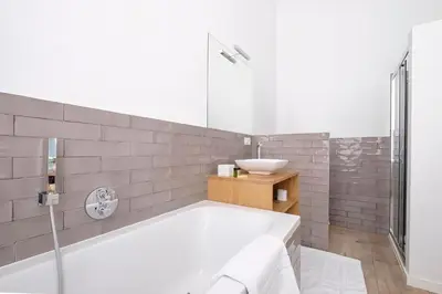 a white bathroom with a tub and a sink at La Calamande En Ville in Brussels