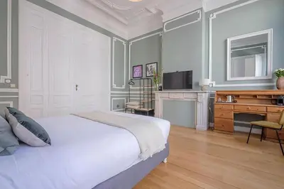 a bedroom with a bed and a desk and a television at La Calamande En Ville in Brussels