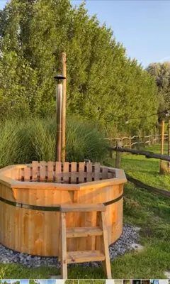 a wooden tub with a wooden chair in a field at Comfort Tipi Marie, Tipi Bo Deluxe & tent Nicolaï - 'Glamping in stijl' in Lembeke