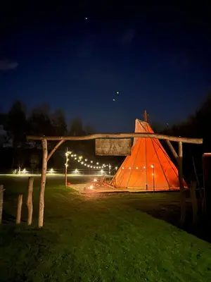 an orange tent in a field at night at Comfort Tipi Marie, Tipi Bo Deluxe & tent Nicolaï - 'Glamping in stijl' in Lembeke